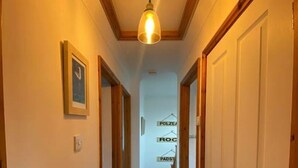 A narrow hallway with wooden doors and a hanging light fixture. - The Meadows St Teath, 4 bed sleeps 7 (Saint Teath)
