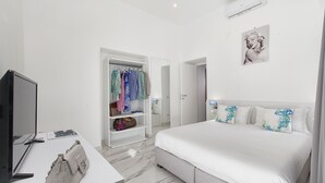 A modern bedroom with a large bed, a TV, a wardrobe, and a mirror.