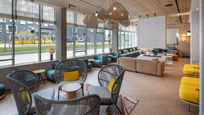 A modern lounge area with wicker furniture, a sofa set, and a view of the outdoors. - Residence Inn by Marriott Paris Charles de Gaulle Airport (Roissy-en-France)