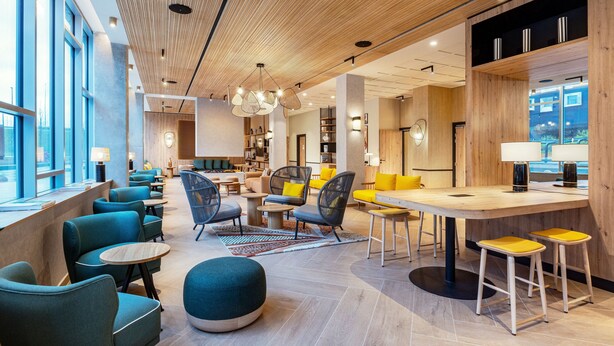 A modern hotel lobby with seating areas, a bar, and large windows. - Residence Inn by Marriott Paris Charles de Gaulle Airport (Roissy-en-France)