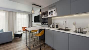 A modern kitchen with a central island, bar stools, a microwave, and a sink.