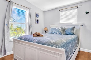 A bedroom with a bed, curtains, a window, and wall art.