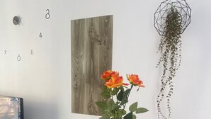 Una mesa de comedor con un mantel individual de estampado geométrico, un jarrón con flores y una planta colgante.