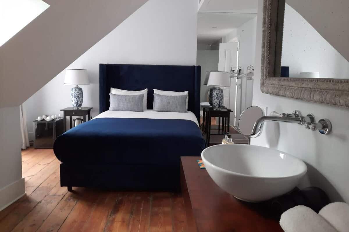 Un dormitorio con una cama grande, un lavamanos blanco y un espejo.
