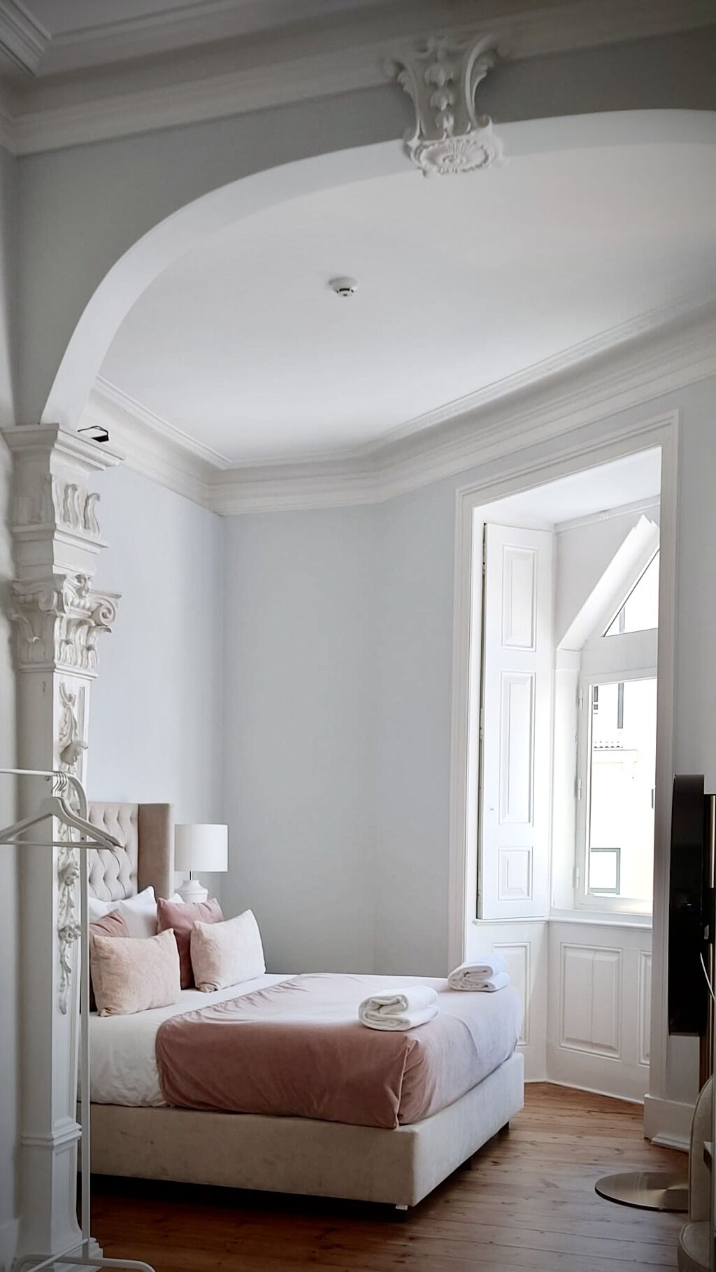 Un dormitorio con una cama grande, una lámpara colgante y vistas al exterior a través de una puerta abierta.