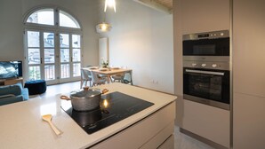 A modern kitchen with a large island, built-in ovens, and a dining area with a view through large windows. - Bright and exclusive apartment in the heart of Città Alta renovated to new (Bergamo)