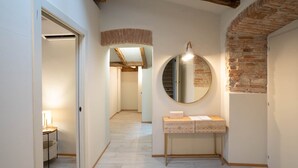 A hallway with a round mirror, a wooden vanity, and a rustic brick wall. - Bright and exclusive apartment in the heart of Città Alta renovated to new (Bergamo)
