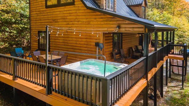 A wooden cabin with a hot tub, deck, and outdoor seating area.