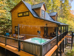 Une cabane en bois dotée d’un bain à remous, d’une terrasse et d’un espace salon extérieur.