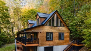 A log cabin with a balcony, a staircase, and a garage.