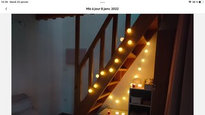 Un escalier décoré de guirlandes lumineuses, une petite table avec des bougies et un fauteuil rembourré.