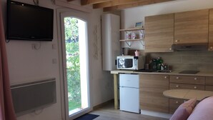 Une cuisine moderne équipée d’un four à micro-ondes encastré, d’un petit réfrigérateur et de meubles de rangement en bois.