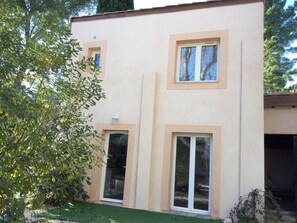 A two-story building with a flat roof, large windows, and a small balcony.