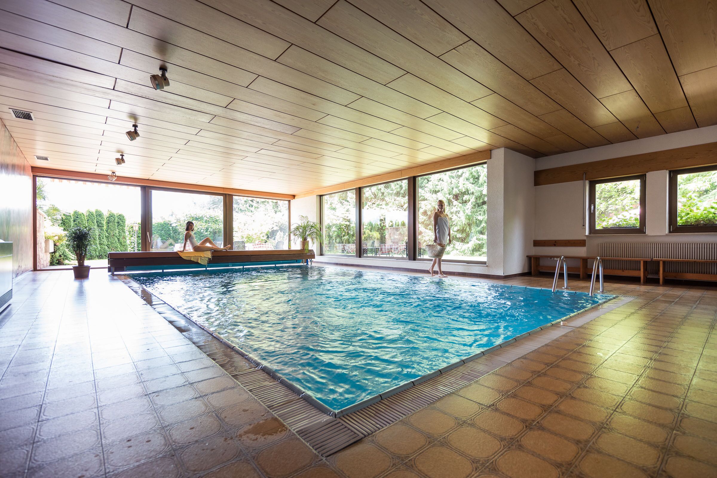 Une piscine intérieure avec un plafond en bois et de grandes fenêtres.