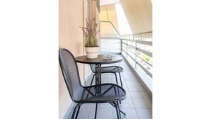 A balcony with a table and two chairs, a potted plant, and a railing. - Suite 06 - Smart Cozy Suites - Cozy, elegant and near the metro (Kallithea, Athens)