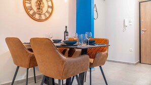 A dining area with a round table, brown chairs, and a wall clock. - Suite 06 - Smart Cozy Suites - Cozy, elegant and near the metro (Kallithea, Athens)