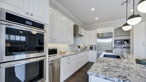 Una cocina moderna con armarios blancos, electrodomésticos de acero inoxidable y encimera de granito.