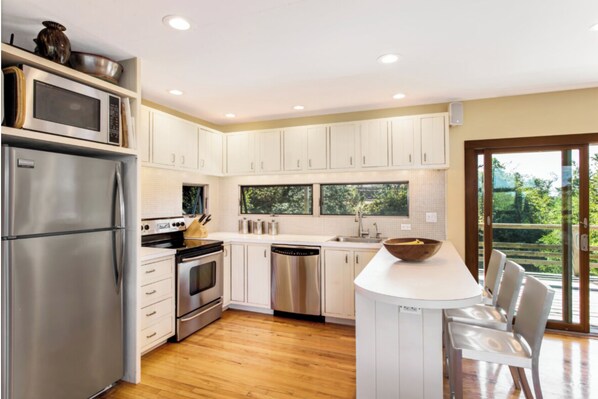 Enjoy cooking in this well-equipped kitchen with a large island, bar seating, and a window overlooking the surrounding greenery.