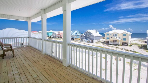Überdachte Veranda mit Blick auf Strandhäuser und das Meer.