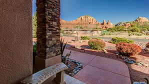 A stone pillar and a bench in a landscaped area with a view of red rock formations. - Experience luxury at Sedona Chapel Area Charm, a spacious 4BR home with stunning red rock views. (Sedona)
