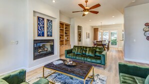 A spacious living room with a fireplace, green velvet sofa, and a ceiling fan. - Experience luxury at Sedona Chapel Area Charm, a spacious 4BR home with stunning red rock views. (Sedona)