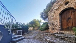 Un bâtiment en pierre avec une porte en bois et un escalier menant à une rambarde en métal.