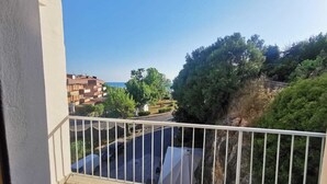 Un balcon donnant sur un quartier résidentiel, une route et une étendue d’eau.