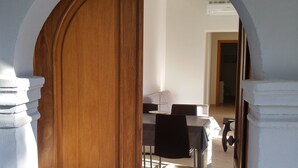 Un portail en arc donne accès à une salle à manger équipée d’une table et de chaises.