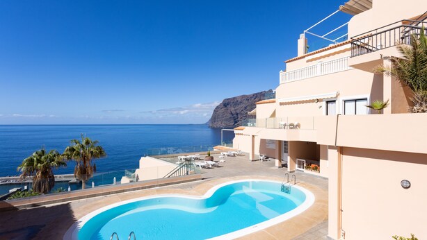 Ein Schwimmbad mit Blick auf das Meer und ein Gebäude mit einem Balkon.