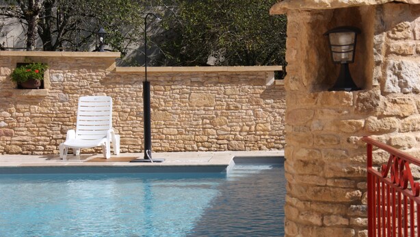 A stone wall with a white lounge chair and a pool. - House (Thenon)