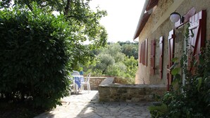 A stone pathway leading to a building with red shutters and a table with a blue tablecloth. - House (Thenon)