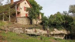 A stone house with a red roof, a balcony, and a stone wall. - House (Thenon)
