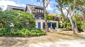 A beachfront property with a thatched-roof building, a pool area with lounge chairs, and lush greenery. - Spacious villa set in the turquoise lagoon of Trou d'eau Douce (Trou d'Eau Douce)