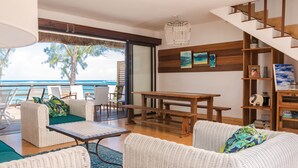 A modern living room with wicker furniture, a wooden table, and a staircase. - Spacious villa set in the turquoise lagoon of Trou d'eau Douce (Trou d'Eau Douce)