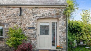 A stone building with a white door, a sign reading "Little Waddons," and two potted plants on the porch. - Luxury self-contained cottage for two with wood fired hot tub (Staverton)