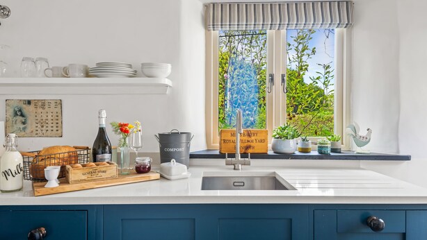 A kitchen with a large window, a sink, and various kitchen items on the counter. - Luxury self-contained cottage for two with wood fired hot tub (Staverton)