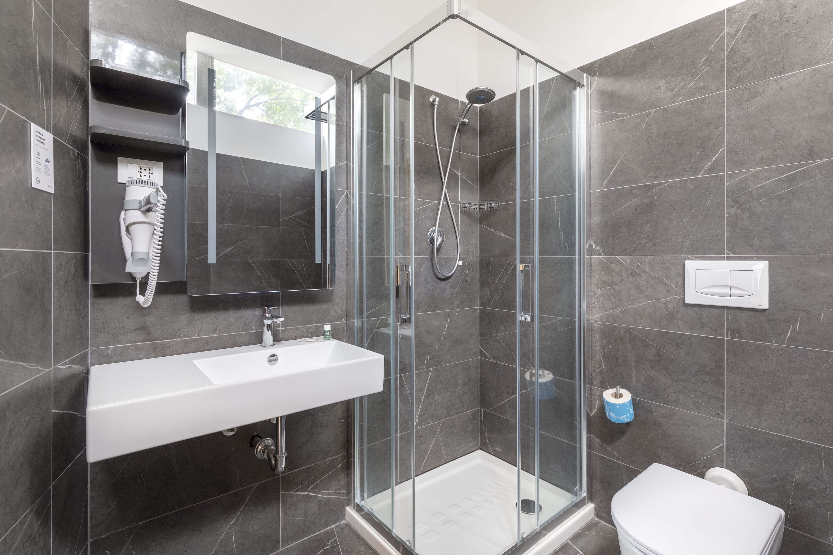 A modern bathroom with a glass-enclosed shower, a white sink, and a toilet.