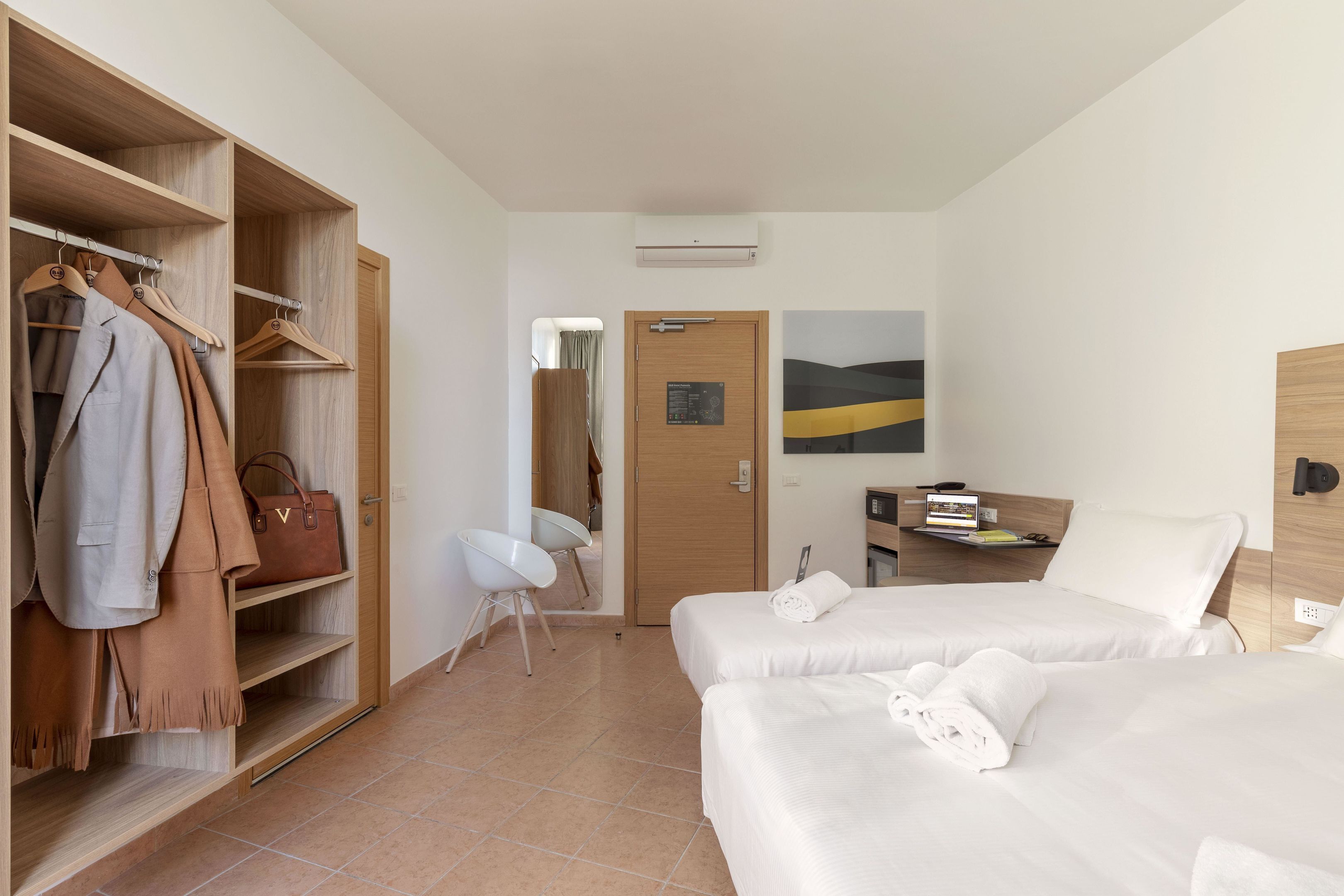 Habitación de hotel con un armario de madera, dos camas, un escritorio y una silla.