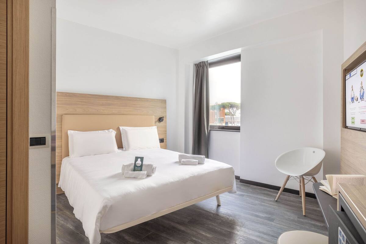 Quarto de hotel moderno com uma cama grande, uma mesa e uma cadeira.