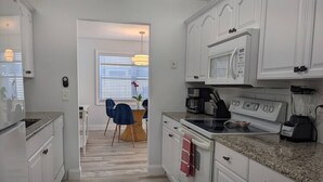 A modern kitchen with white cabinetry, a granite countertop, and a built-in microwave.