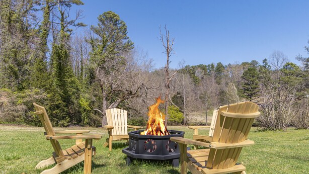 A fire pit with chairs around it in a grassy outdoor area. - Charming 1892 Log Cabin in the Blue Ridge Mountains foothills (Rutherfordton)