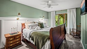 A bedroom with a bed, nightstand, dresser, rocking chair, and a ceiling fan. - Outdoor Pool ● Near Boone & Elk ● Fire Pit ● Games ● Kids Bunks (Banner Elk)
