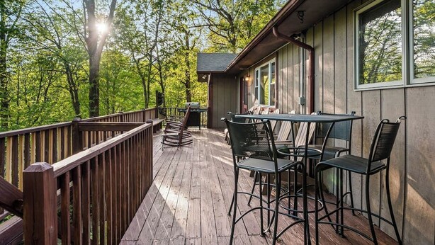 A wooden deck with outdoor seating and a view of trees. - Outdoor Pool ● Near Boone & Elk ● Fire Pit ● Games ● Kids Bunks (Banner Elk)