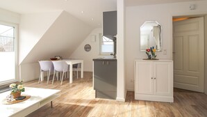 A modern kitchen with a dining area, a small refrigerator, and a cabinet with a mirror.