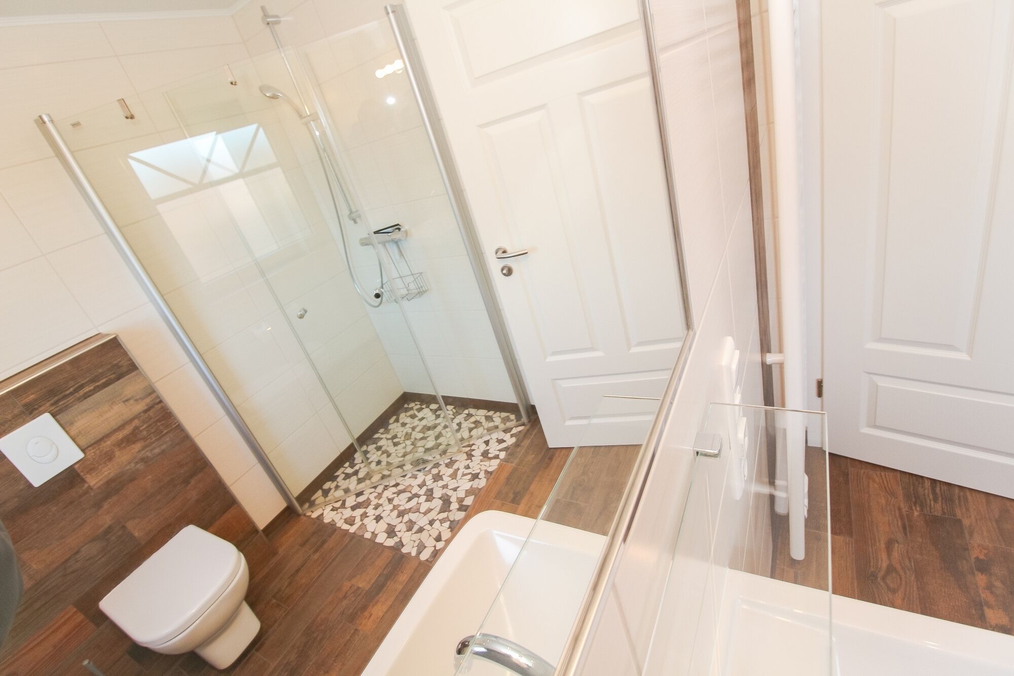 Un baño moderno con ducha envuelta en vidrio, inodoro y lavamanos.