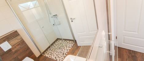Un baño moderno con ducha envuelta en vidrio, inodoro y lavamanos.