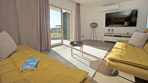 A modern hotel room with a sofa bed, a flat-screen TV, a small side table, and a large window with a view. - Villa w/ heatable pool, BBQ & private annexes (Albufeira)