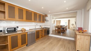 A modern kitchen with wooden cabinets, a built-in microwave, and a dishwasher. - Villa w/ heatable pool, BBQ & private annexes (Albufeira)