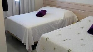 Habitación de hotel con dos camas individuales, una ventana con cortinas y una lámpara en el techo.