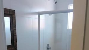 Un baño pequeño y moderno con inodoro, lavamanos y ducha.